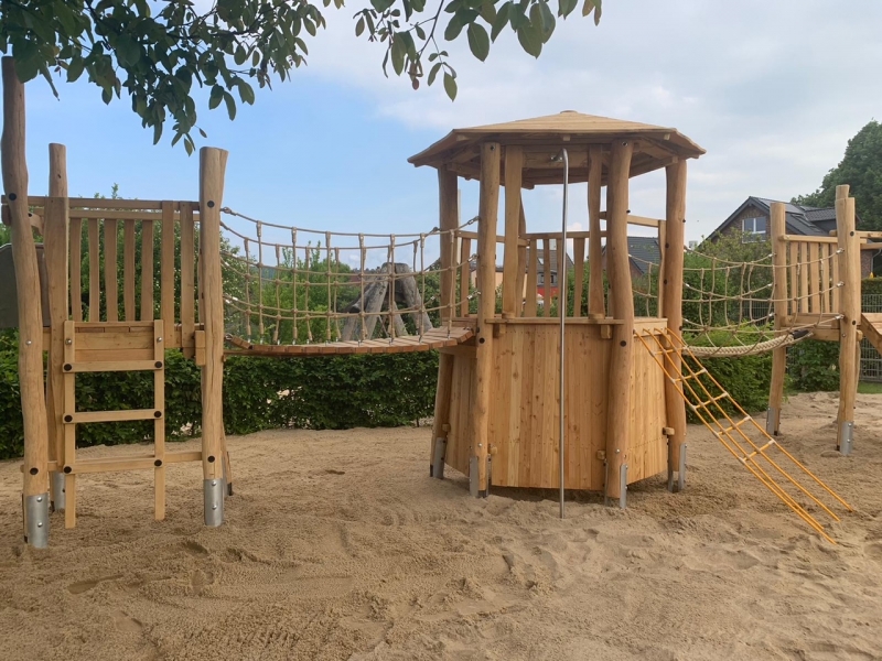 Eine Kletteranlage mit Rutsche, Feuerwehrstange, Kletternetz, Kletterwand und Hängebrücke, sowie eine Vogelnestschaukel und ein Sand - Matschbereich regen zum Spielen und Klettern an.